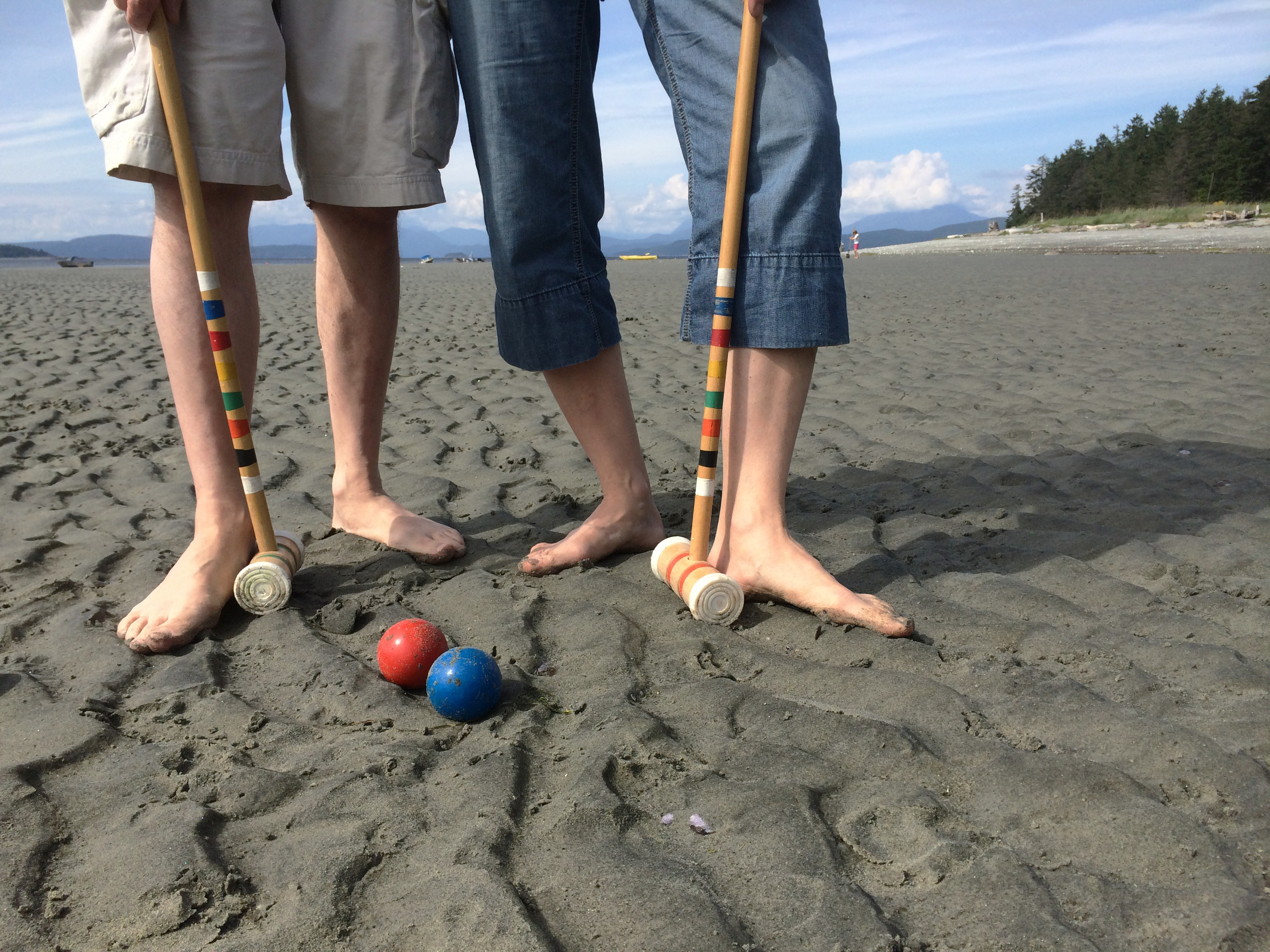 2 people's legs on the beach playing beach croquet