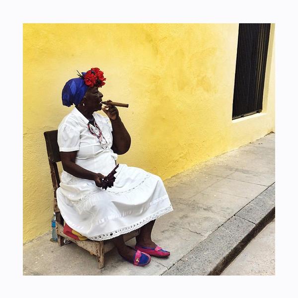 Beautiful cuban woman smoking a cigar against a yellow wall. Photo print by Instagrammer and mobile photographer Colleen Lammer.  This print and another 11 for sale on the Impressed Print Shop